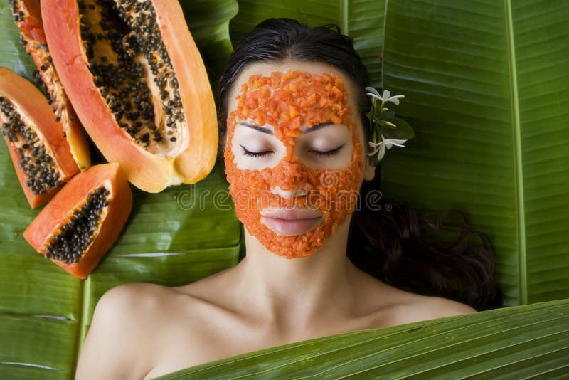A mulher bonita que tem a máscara facial da papaia fresca aplica-se pap fresco