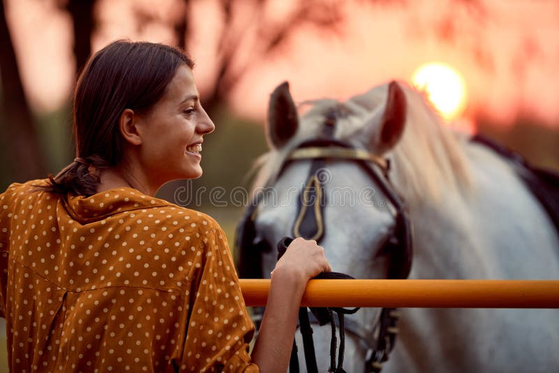 Mulher Bonita Sorrindo Em Frente Ao Cavalo No Pôr Do Sol Imagem de