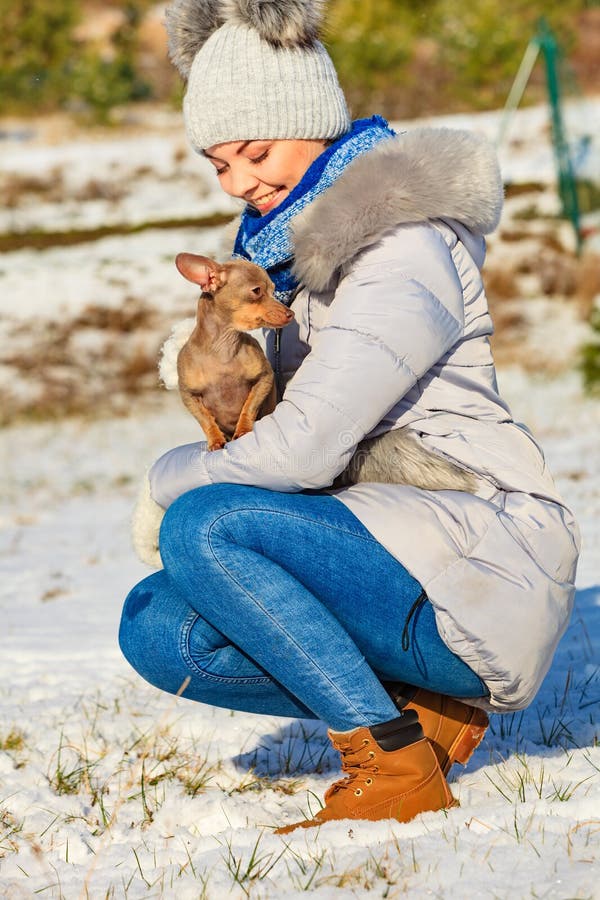 Mulher brincando com cachorro durante o inverno fotografia de stock