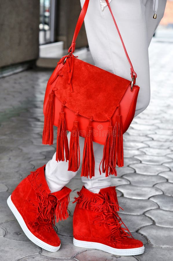 Mulher bronzeada magro que veste os saltos altos vermelhos com borlas e o saco vermelho com franja Fôrma da rua Olhar da rua da f imagens de stock royalty free Mulher bronzeada magro que veste os saltos altos vermelhos com borlas e o saco vermelho com franja Fôrma da rua Olhar da rua da f imagens de stock royalty free