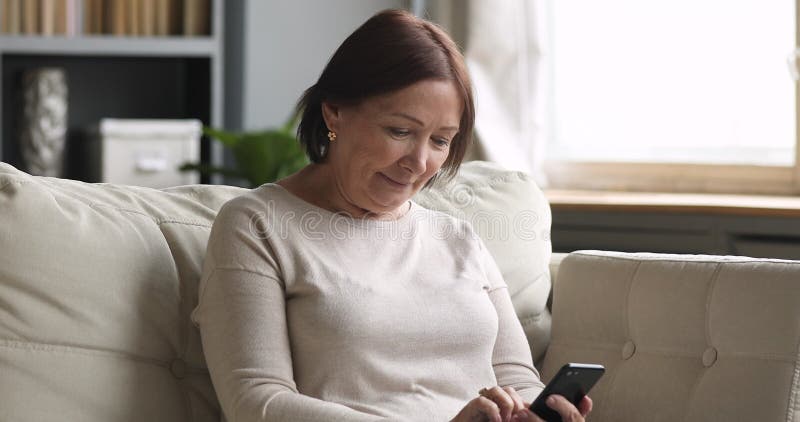 Mulher brunette de meia-idade feliz usando aplicativos móveis.