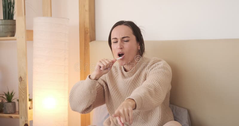 Mulher cantando e dançando sentada na cama