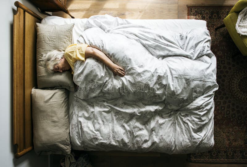 Mulher caucasiano idosa que dorme na cama imagens de stock Mulher caucasiano idosa que dorme na cama imagens de stock