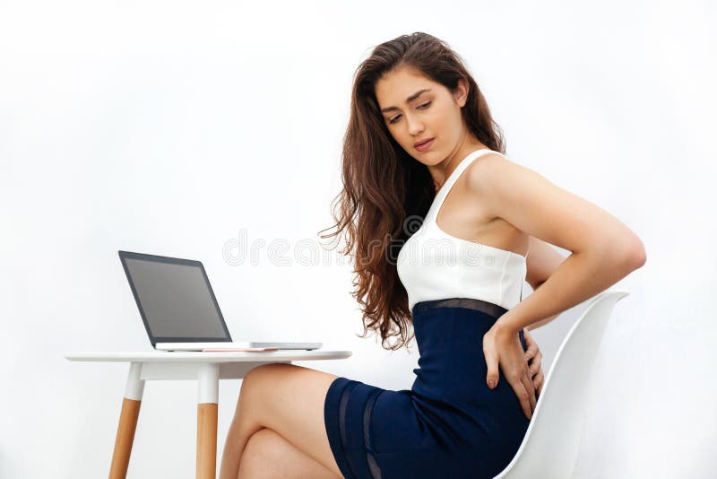 Mulher caucasiano nova que tem a dor nas costas/dor lombar/síndrome crônicas do escritório ao trabalhar com o portátil na mesa br fotos de stock royalty free Mulher caucasiano nova que tem a dor nas costas/dor lombar/síndrome crônicas do escritório ao trabalhar com o portátil na mesa br fotos de stock royalty free