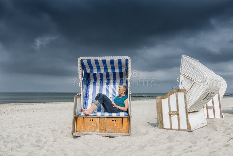 Mulher caucasiana a relaxar num strandkorb na costa do Mar Báltico imagem de stock