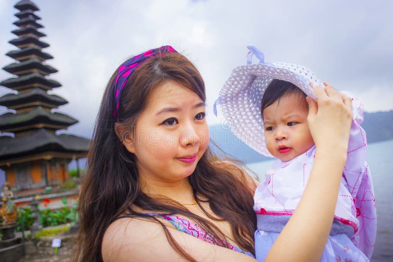 Mulher chinesa asiática bonita feliz nova como a mãe de amor que guarda o bebê adorável da filha durante a visita da excursão dos foto de stock royalty free Mulher chinesa asiática bonita feliz nova como a mãe de amor que guarda o bebê adorável da filha durante a visita da excursão dos foto de stock royalty free