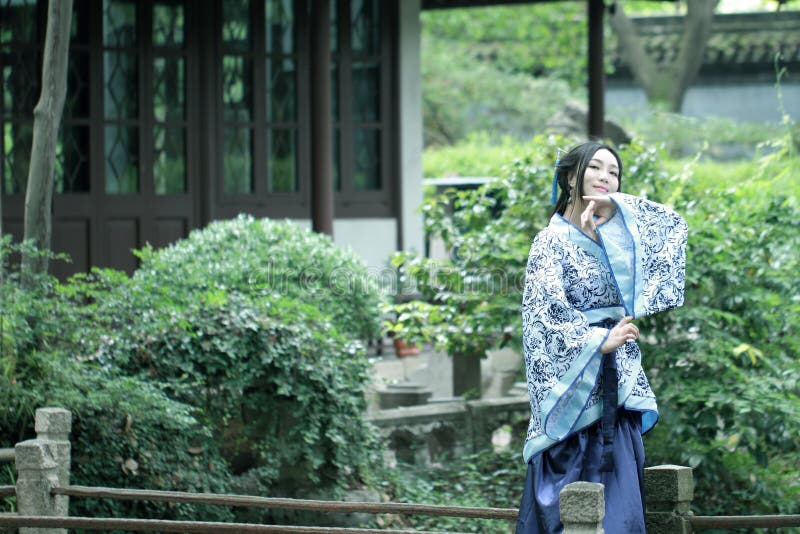 Chinese woman in traditional Blue and white porcelain style Hanfu dress Standing on the winding Bridge at Qiyuan Garden. Qiyuan Garden is one of the ten famous gardens in Chinese. Chinese woman in traditional Blue and white porcelain style Hanfu dress Standing on the winding Bridge at Qiyuan Garden. Qiyuan Garden is one of the ten famous gardens in Chinese