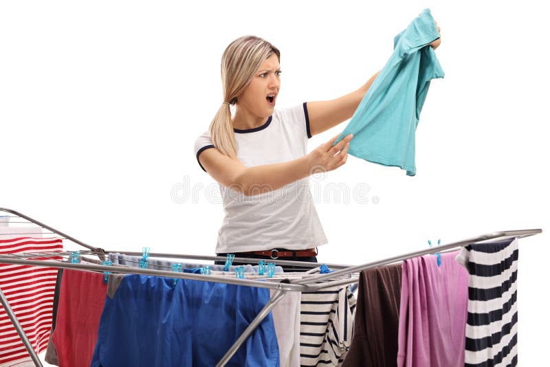Mulher chocada atrás de um secador da cremalheira da roupa que olha uma camisa fotografia de stock Mulher chocada atrás de um secador da cremalheira da roupa que olha uma camisa fotografia de stock