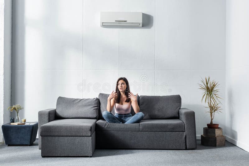 Mulher chocada em lotus pose sentada no sofá imagens de stock