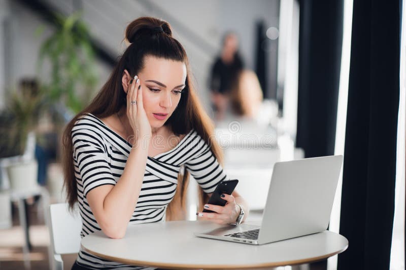 Mulher chocada que guarda e que olha tristemente no telefone celular, é desapontado e confundida com mensagem recebida fotografia de stock Mulher chocada que guarda e que olha tristemente no telefone celular, é desapontado e confundida com mensagem recebida fotografia de stock