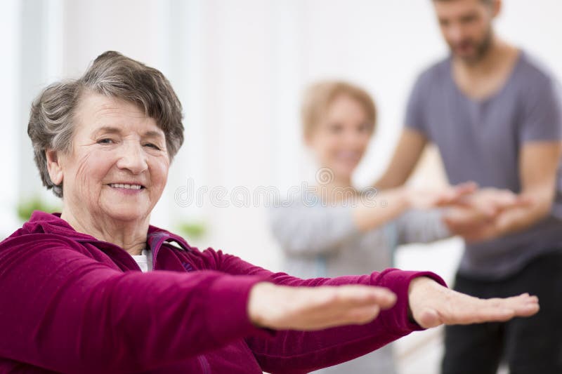 Mulher cinzenta superior que exercita no centro da fisioterapia do hospital imagem de stock Mulher cinzenta superior que exercita no centro da fisioterapia do hospital imagem de stock