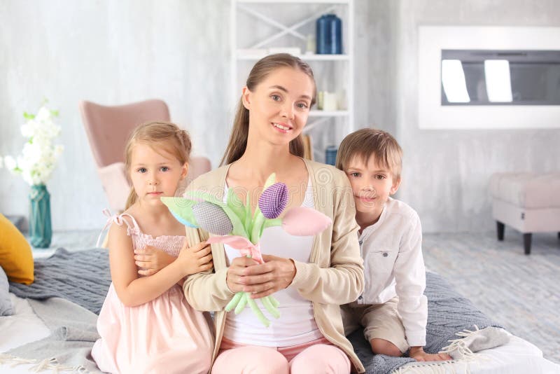 Mulher com as flores artificiais recebidas de suas crianças para o dia de mãe em casa fotografia de stock Mulher com as flores artificiais recebidas de suas crianças para o dia de mãe em casa fotografia de stock