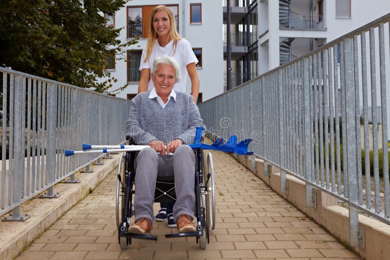 Mulher com a cadeira de rodas na rampa