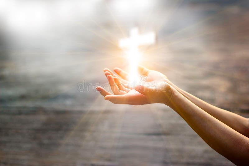 Mulher com cruz branca nas mãos que reza na luz solar