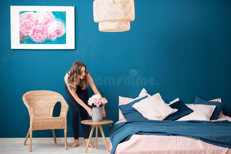 Young woman decorating bedroom with beautiful flowers at home. Young woman decorating bedroom with beautiful flowers at home