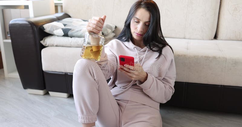 Mulher com garrafa de álcool e um smartphone está sentado no chão filme