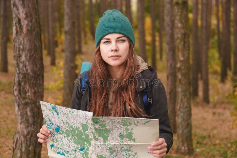 Mulher com mapa do curso e trouxa na floresta do pinho foto de stock Mulher com mapa do curso e trouxa na floresta do pinho foto de stock