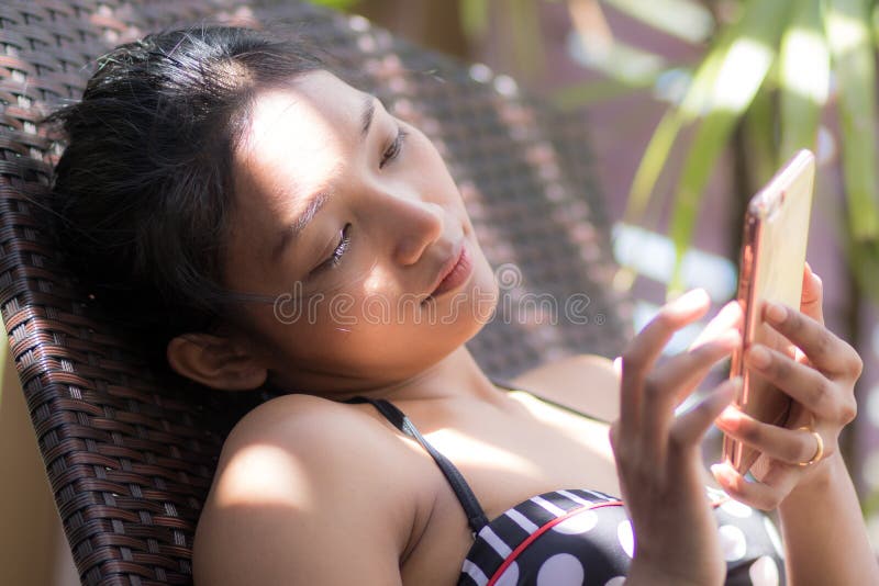 Mulher com o banho de sol do telefone celular no vadio