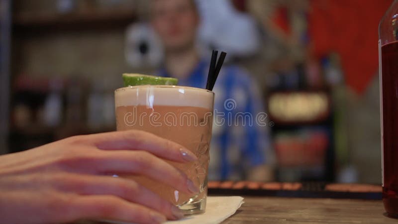 A mulher com tratamento de mãos bonito leva embora o cocktail do contador da barra