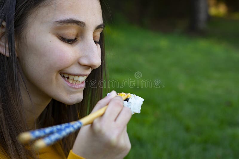 Mulher comendo sushi sentada na grama imagens de stock royalty free
