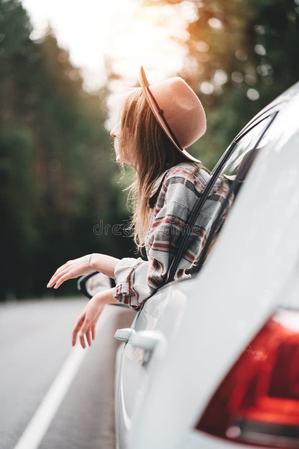 Mulher considerável que senta-se no carro que olha da janela na vista bonita no moderno bonito da menina da floresta que aprecia imagem de stock royalty free Mulher considerável que senta-se no carro que olha da janela na vista bonita no moderno bonito da menina da floresta que aprecia imagem de stock royalty free