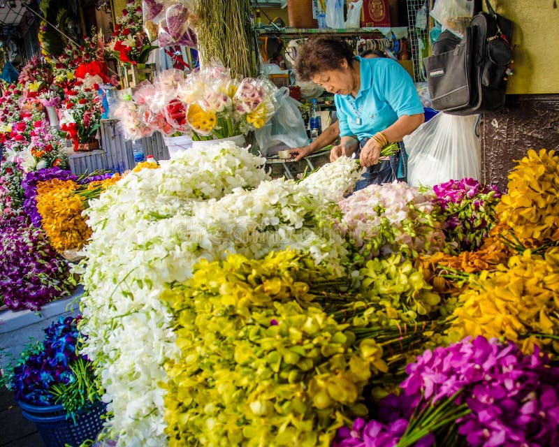 A mulher cria arranjos florais para a venda em um mercado exterior em Banguecoque foto de stock royalty free A mulher cria arranjos florais para a venda em um mercado exterior em Banguecoque foto de stock royalty free