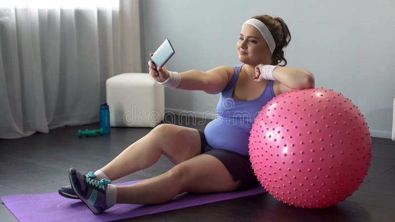Mulher curvy presumido que faz o selfie no smartphone durante o exercício home fotografia de stock Mulher curvy presumido que faz o selfie no smartphone durante o exercício home fotografia de stock