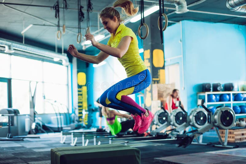 Mulher da aptidão que salta no treinamento no gym, ajuste da caixa da cruz fotografia de stock Mulher da aptidão que salta no treinamento no gym, ajuste da caixa da cruz fotografia de stock