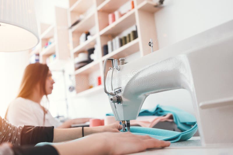Mulher da costureira que trabalha na máquina de costura no estúdio A costureira dois que faz o conceito novo da forma veste-se na imagens de stock royalty free Mulher da costureira que trabalha na máquina de costura no estúdio A costureira dois que faz o conceito novo da forma veste-se na imagens de stock royalty free