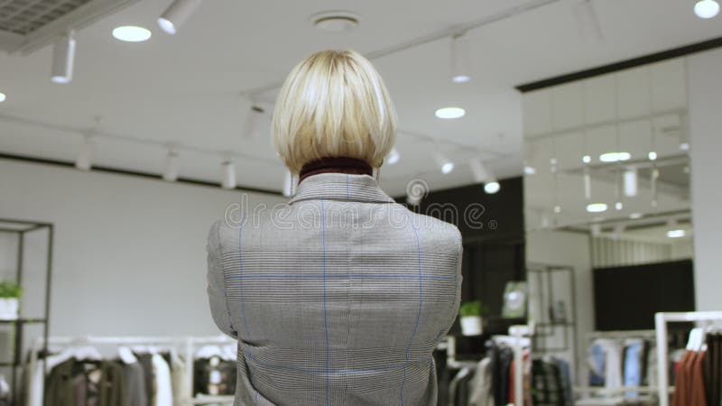 Mulher de cabelo curto está tirando uma selfie na loja de roupas vestida com um traje cinza com um tiro de localização de 360 grau