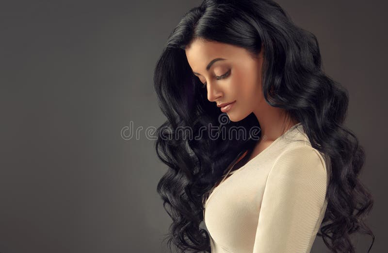 Mulher de cabelo preta nova com cabelo volumoso, brilhante e ondulado