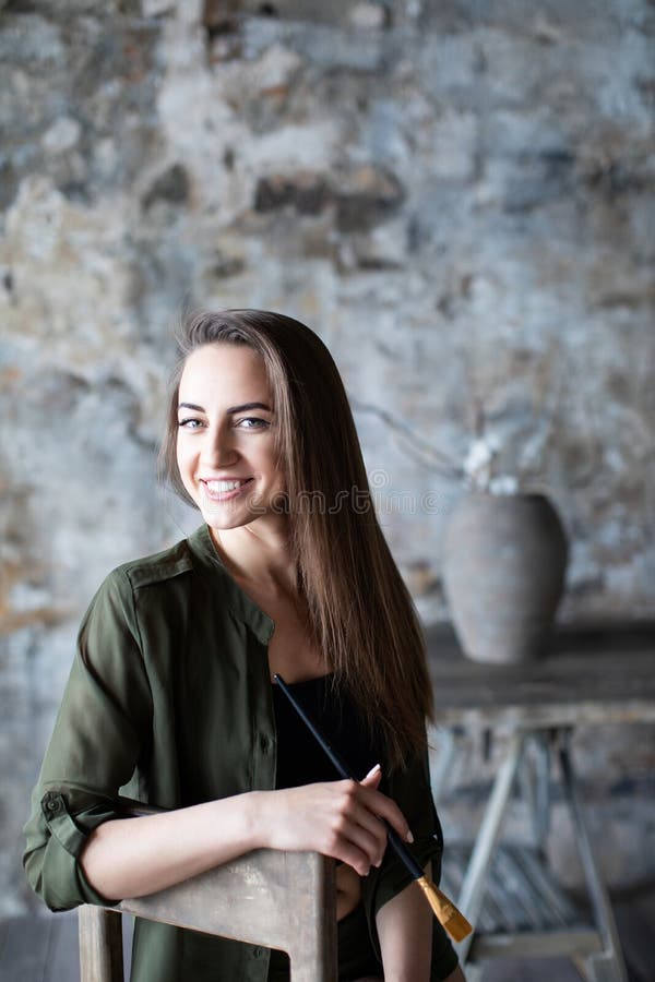 Mulher de cabelos compridos de sorriso com uma escova em sua mão fotografada em um estúdio da arte imagem de stock Mulher de cabelos compridos de sorriso com uma escova em sua mão fotografada em um estúdio da arte imagem de stock