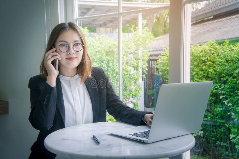 Mulher de funcionamento, estilo asiático novo da mulher de negócio falando em smar foto de stock Mulher de funcionamento, estilo asiático novo da mulher de negócio falando em smar foto de stock