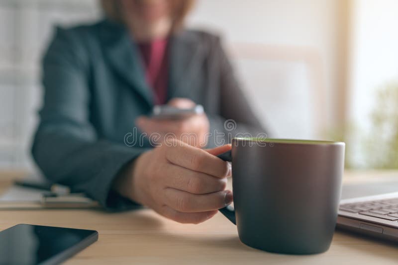 Mulher de neg?cios que texting no telefone celular durante a ruptura de caf? do escrit?rio imagem de stock Mulher de neg?cios que texting no telefone celular durante a ruptura de caf? do escrit?rio imagem de stock