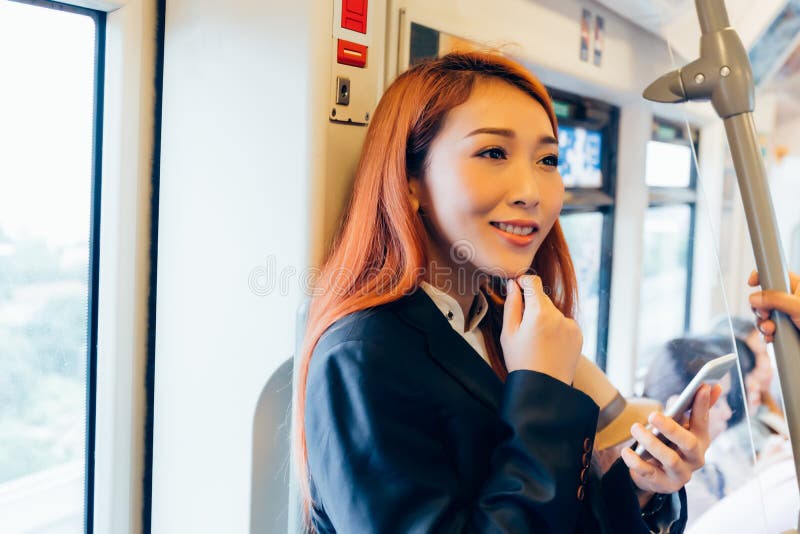 Mulher de negócio asiática bonita feliz que joga um telefone ao montar o imagem de stock royalty free Mulher de negócio asiática bonita feliz que joga um telefone ao montar o imagem de stock royalty free