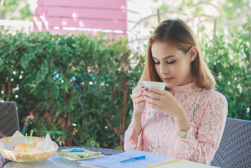 A mulher de negócio asiática é de trabalho e bebendo o café em exterior foto de stock A mulher de negócio asiática é de trabalho e bebendo o café em exterior foto de stock