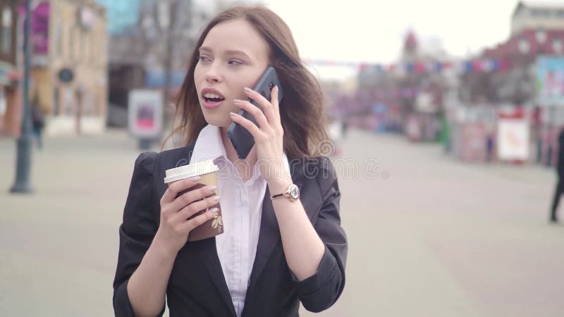 Mulher de negócio moreno atrativa que usa Smartphone na cidade Mulher de negócio consideravelmente nova que fala pelo telefone e