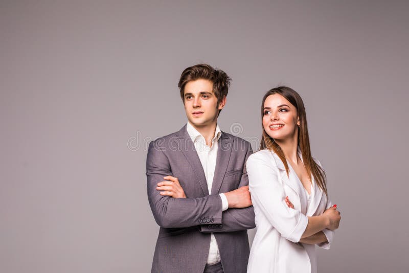 Mulher de negócio nova e homem de negócio de sorriso isolado no fundo cinzento imagens de stock royalty free Mulher de negócio nova e homem de negócio de sorriso isolado no fundo cinzento imagens de stock royalty free
