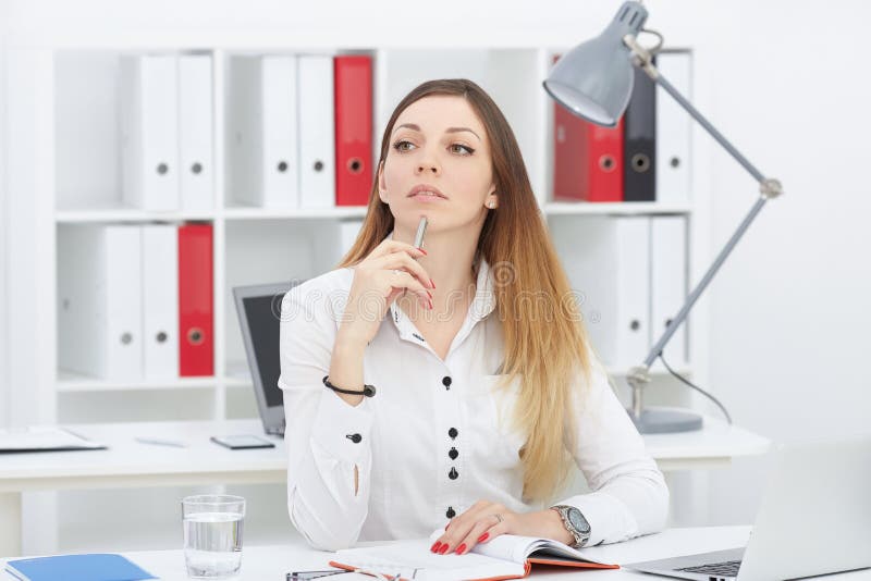 Mulher de negócio pensativa bonita que senta-se no local de trabalho do escritório que olha na distância fotografia de stock Mulher de negócio pensativa bonita que senta-se no local de trabalho do escritório que olha na distância fotografia de stock