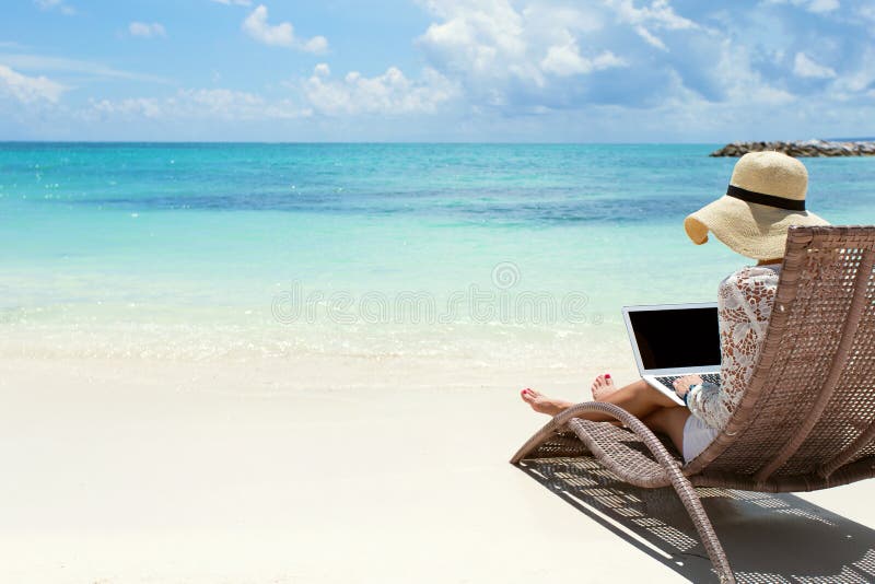 Mulher de negócio que usa o laptop na praia