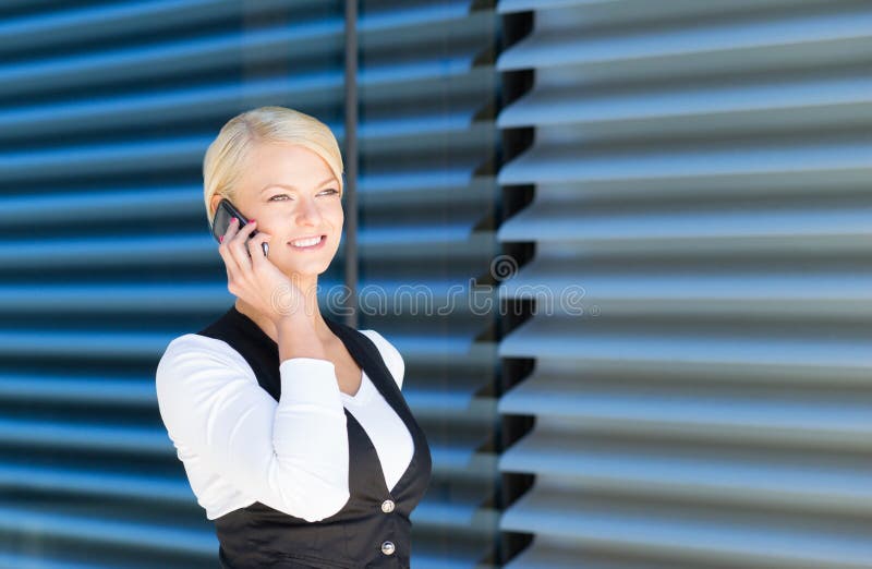 Mulher de negócios bonita que arranja uma reunião pelo telefone fotografia de stock Mulher de negócios bonita que arranja uma reunião pelo telefone fotografia de stock