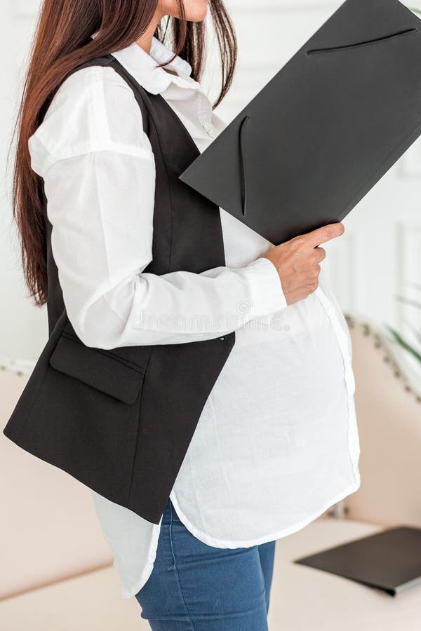 Mulher de negócios grávida no trabalho em um escritório que lê um documento fotos de stock Mulher de negócios grávida no trabalho em um escritório que lê um documento fotos de stock