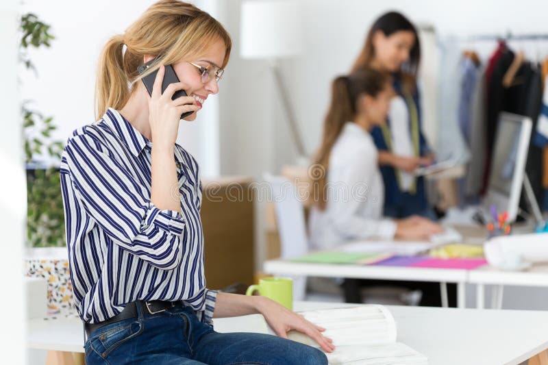Mulher de negócios nova bonita que usa seu telefone celular para trabalhar no escritório fotos de stock Mulher de negócios nova bonita que usa seu telefone celular para trabalhar no escritório fotos de stock