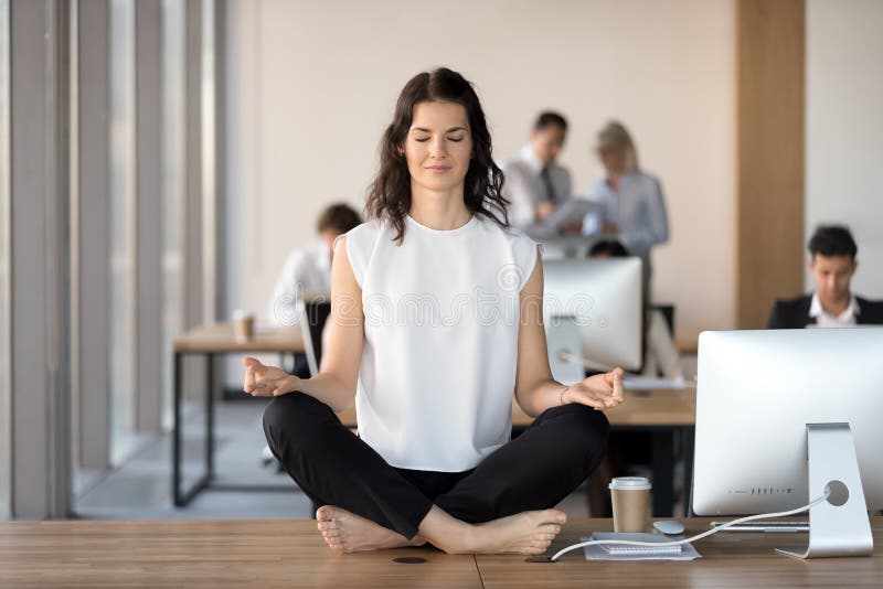 Mulher de negócios nova calma que faz o exercício da ioga na mesa do trabalho imagens de stock royalty free Mulher de negócios nova calma que faz o exercício da ioga na mesa do trabalho imagens de stock royalty free