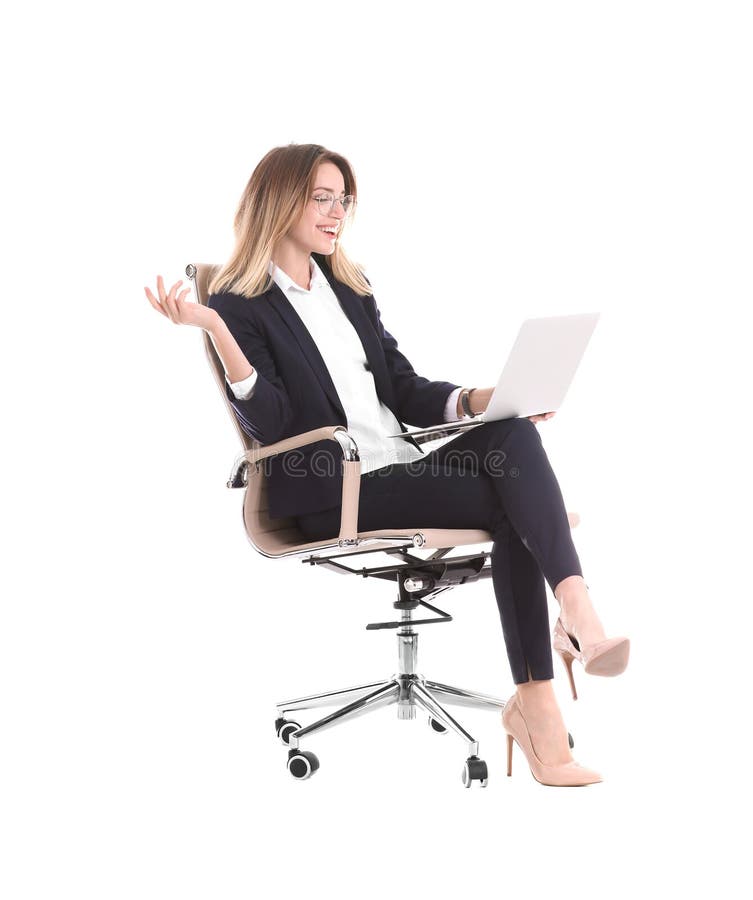 Mulher de negócios nova com o portátil que senta-se na cadeira do escritório foto de stock Mulher de negócios nova com o portátil que senta-se na cadeira do escritório foto de stock