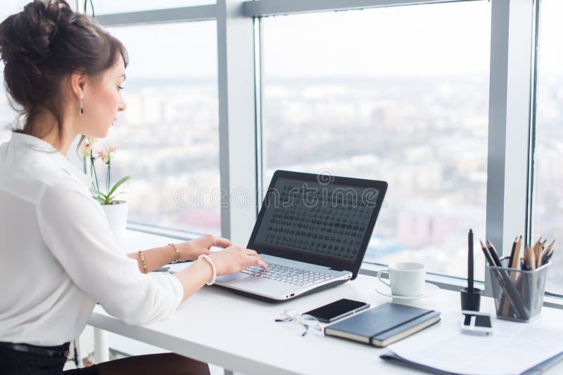 Mulher de negócios nova que trabalha no escritório, datilografando, usando o computador Mulher concentrada que procura a informaç fotos de stock Mulher de negócios nova que trabalha no escritório, datilografando, usando o computador Mulher concentrada que procura a informaç fotos de stock