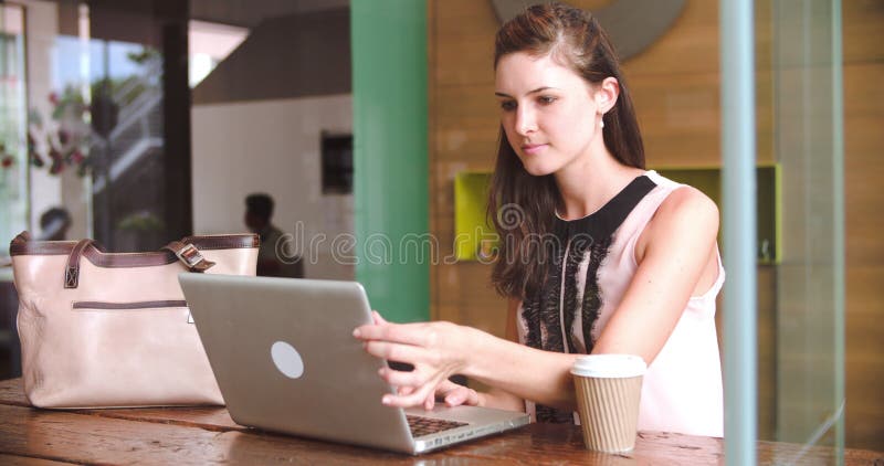 Mulher de negócios nova Working On Laptop na cafetaria