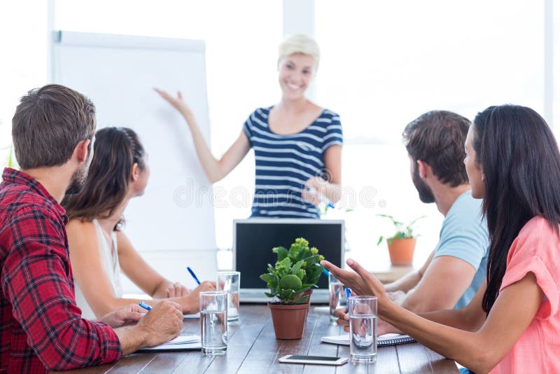 Mulher de negócios ocasional que dá a apresentação a seus colegas imagem de stock royalty free Mulher de negócios ocasional que dá a apresentação a seus colegas imagem de stock royalty free