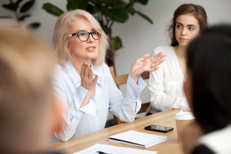 Mulher de negócios, professor ou treinador envelhecido do negócio que fala aos jovens Mulher de negócios, professor ou treinador envelhecido do negócio que fala aos jovens
