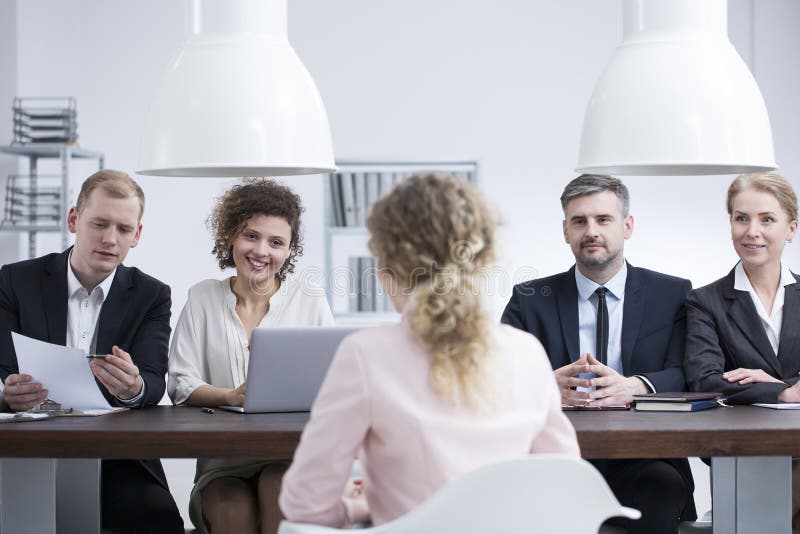 Mulher de negócios que discute o resumo com os recrutas. Mulher de negócios nova que discute seu resumo com uma equipe dos recrutas em um escritório da empresa